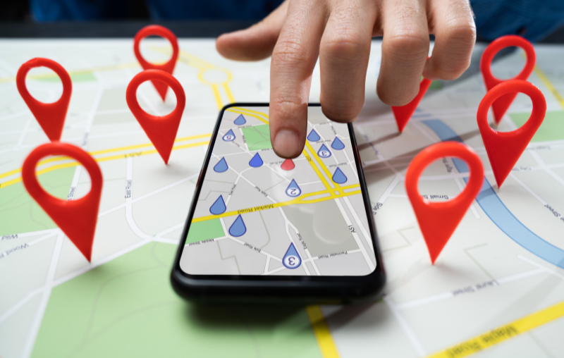 Finger pointing at phone with a map surrounding it.
