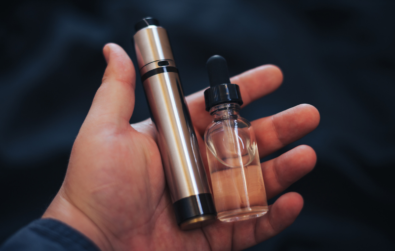 Hand holding a vape and liquid.