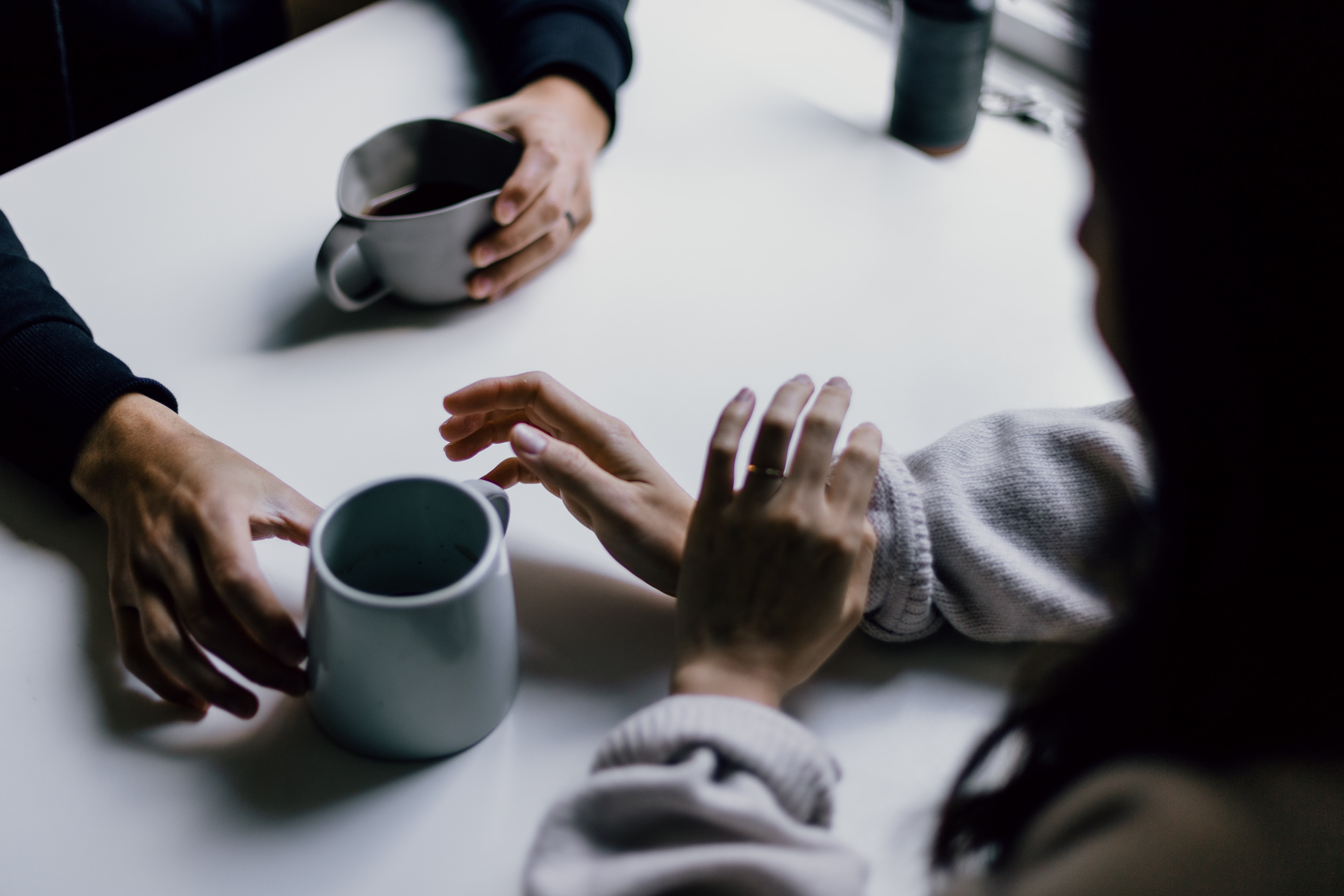 Two people having a conversation with cups of coffee on the table