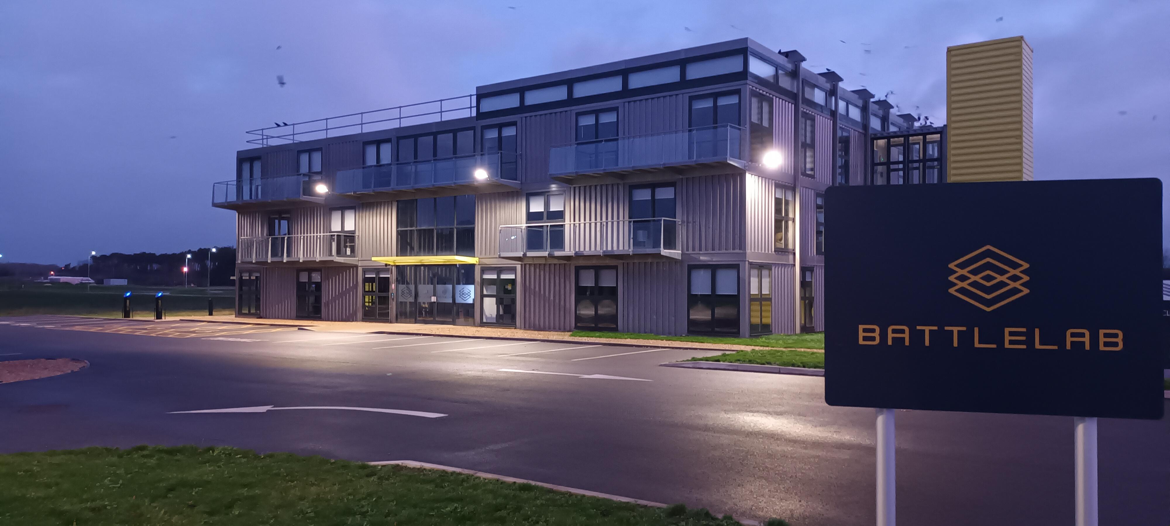 A night time view of an industrial looking building and a sign that says Battlelab