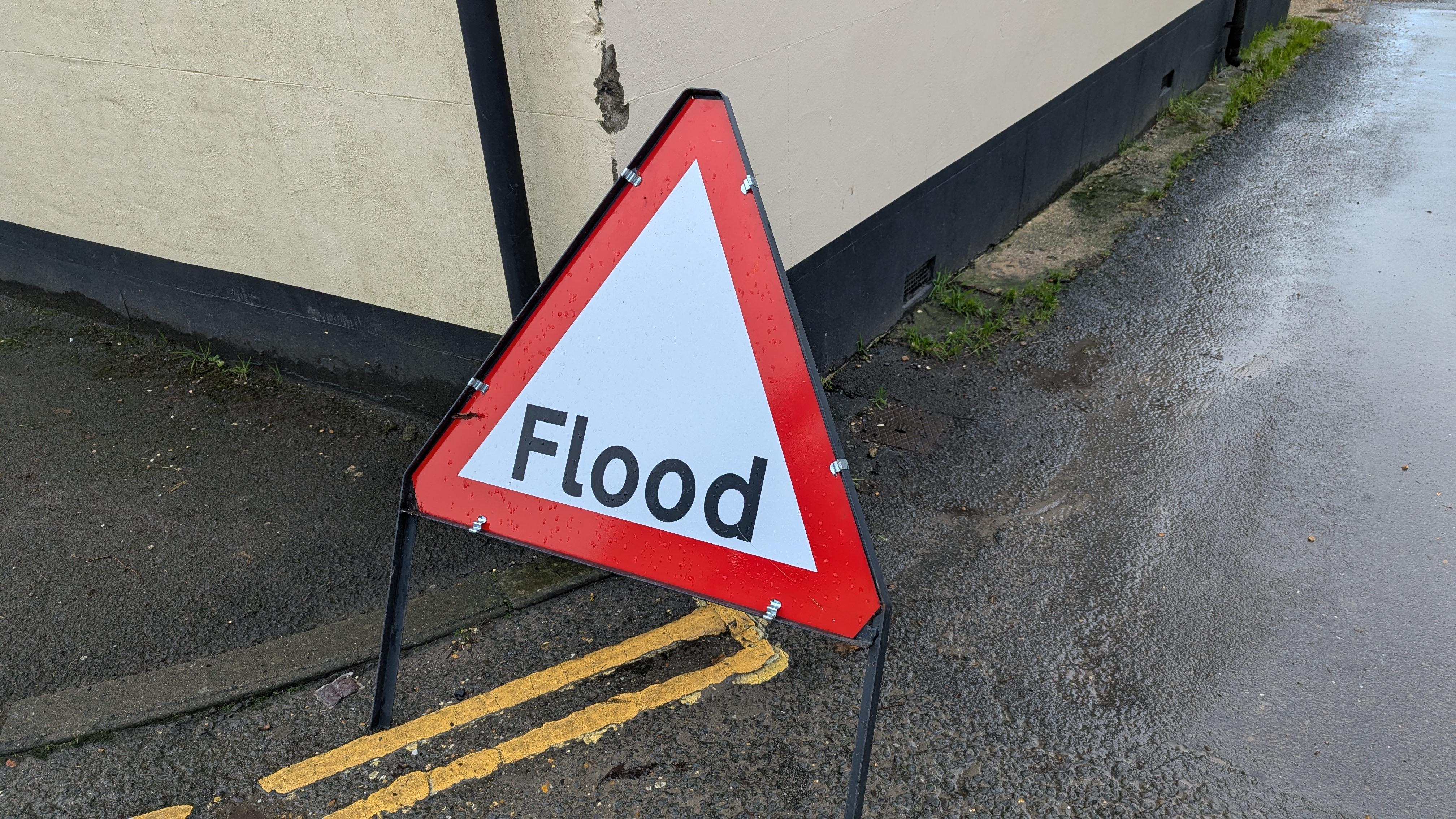 Road sign, text "Flood", on residential street
