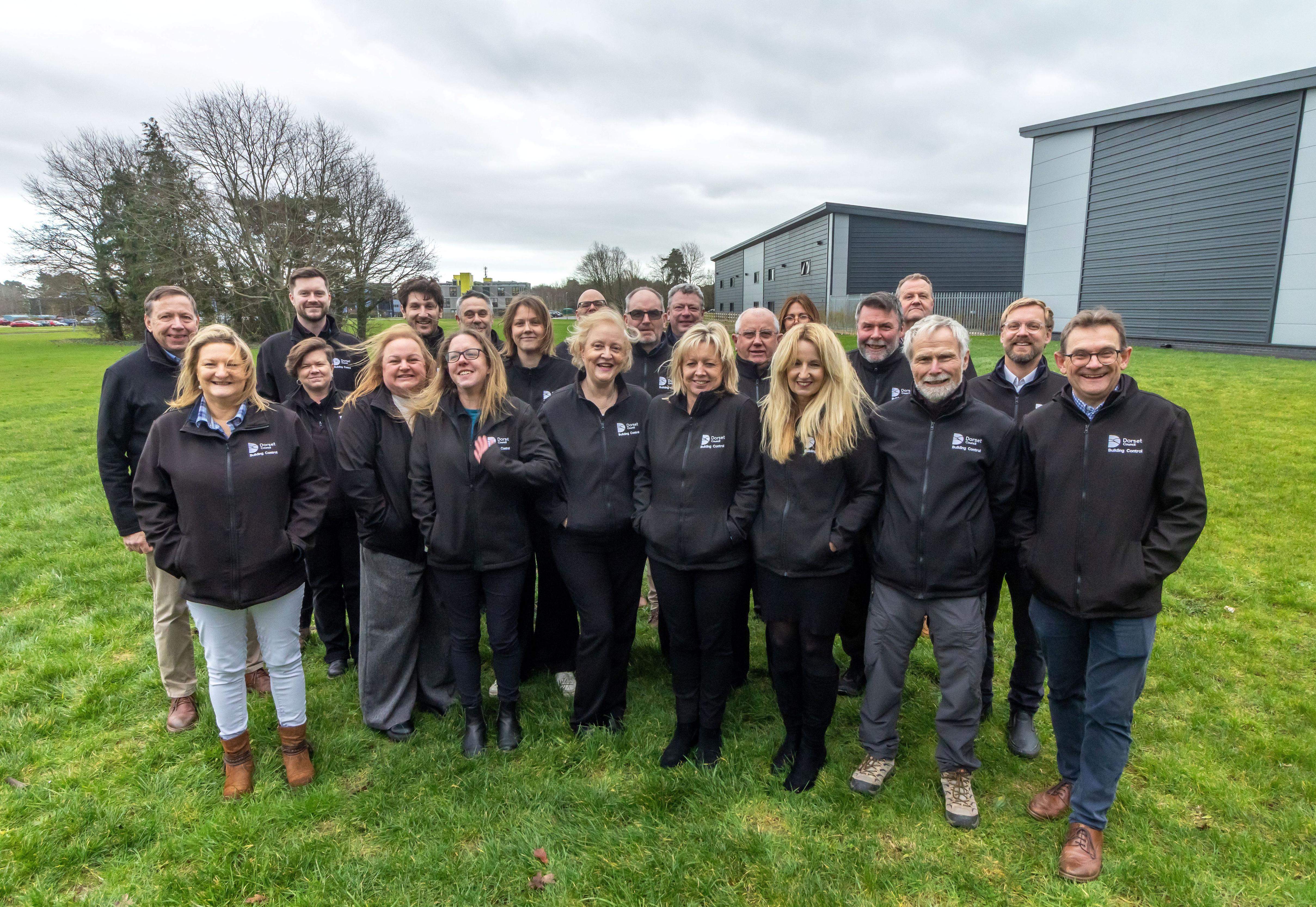 A group of men and women wearing black jackets with Dorset Council logo on.